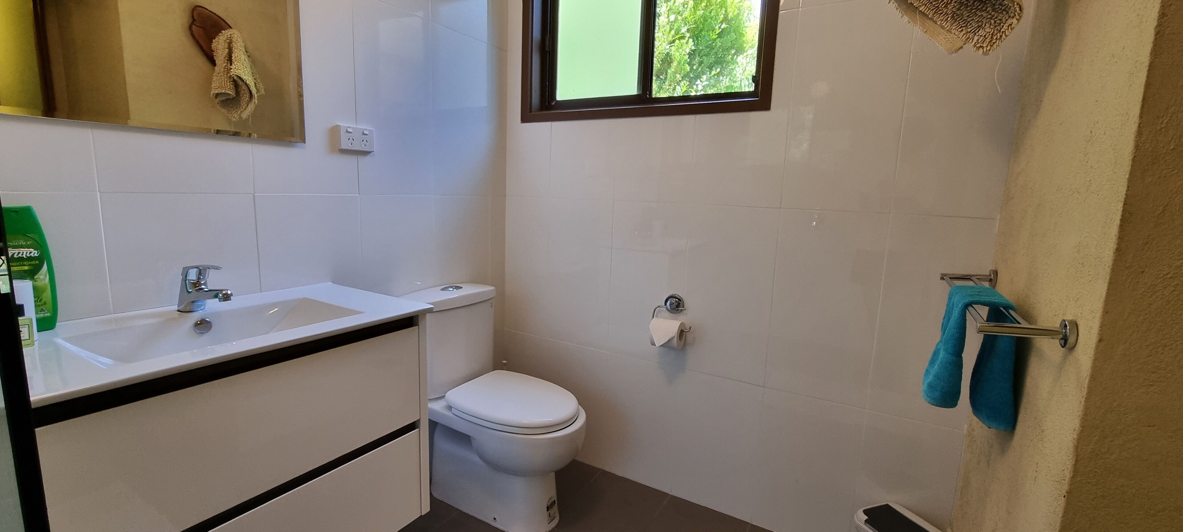 Un baño con lavamanos blanco, inodoro y toallero con una toalla azul.
