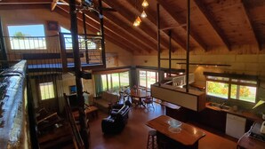 Un intérieur spacieux avec un plafond haut, des poutres en bois, un coin repas et une cuisine.