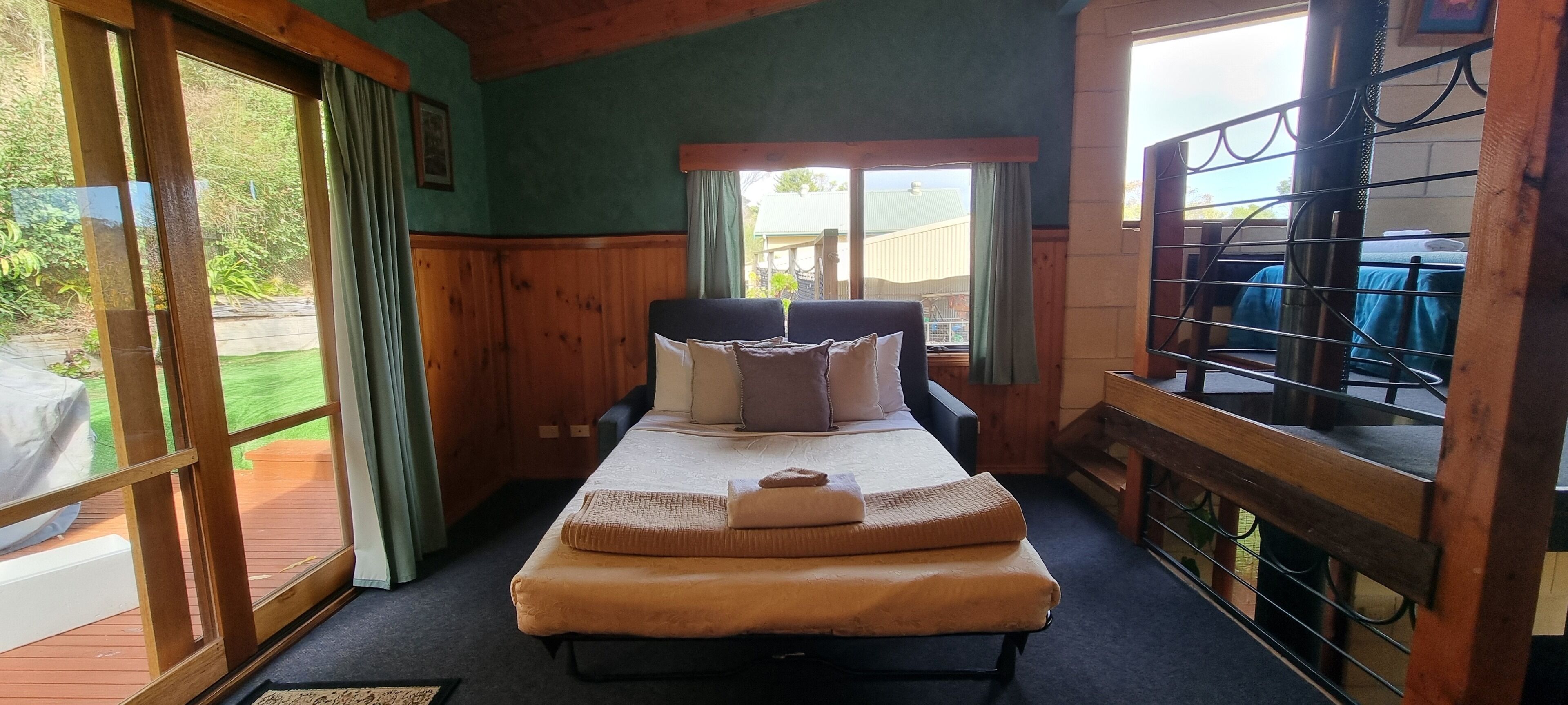 Ein Zimmer mit einem Bett, einer Holzbank und Blick ins Freie.