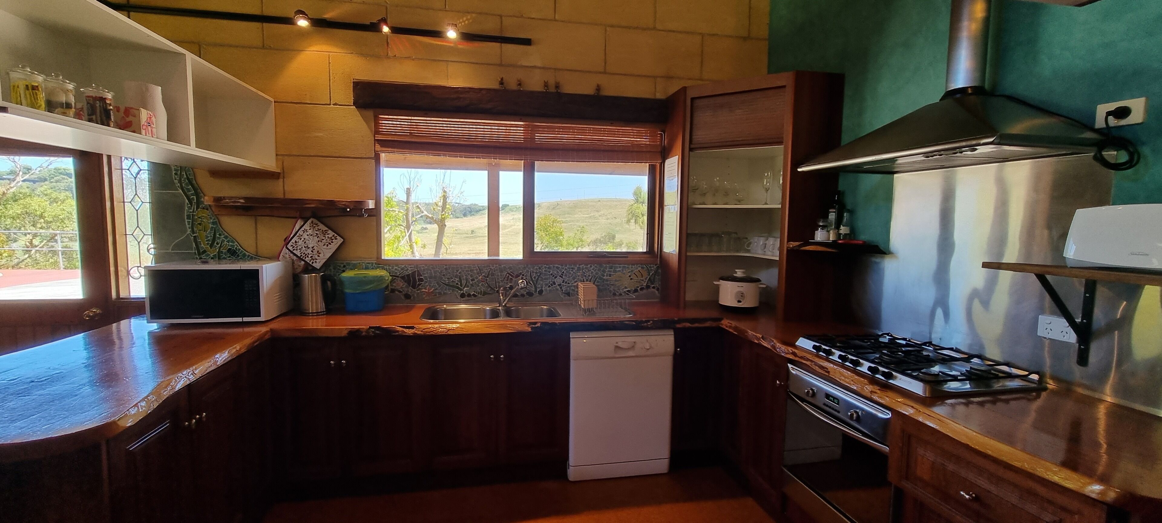 Uma cozinha com armários de madeira, forno embutido, fogão a gás e janela com vista para o exterior.