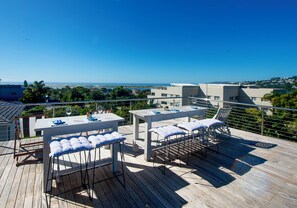 Una terraza de madera con una mesa y sillas, con vista a un paisaje costero.