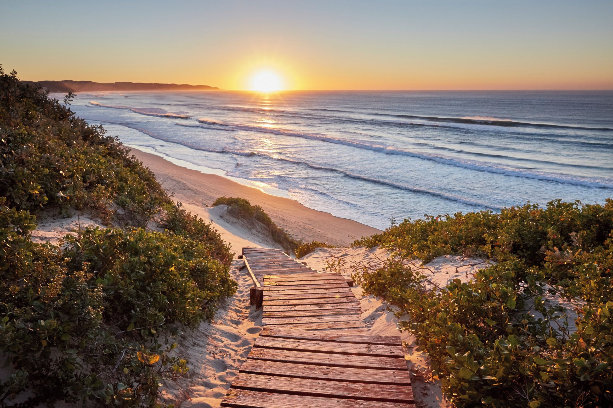 A wooden pathway leading to a beach with ocean views.