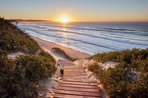 A wooden pathway leading to a beach with ocean views. - Prana Lodge (Great Kei)