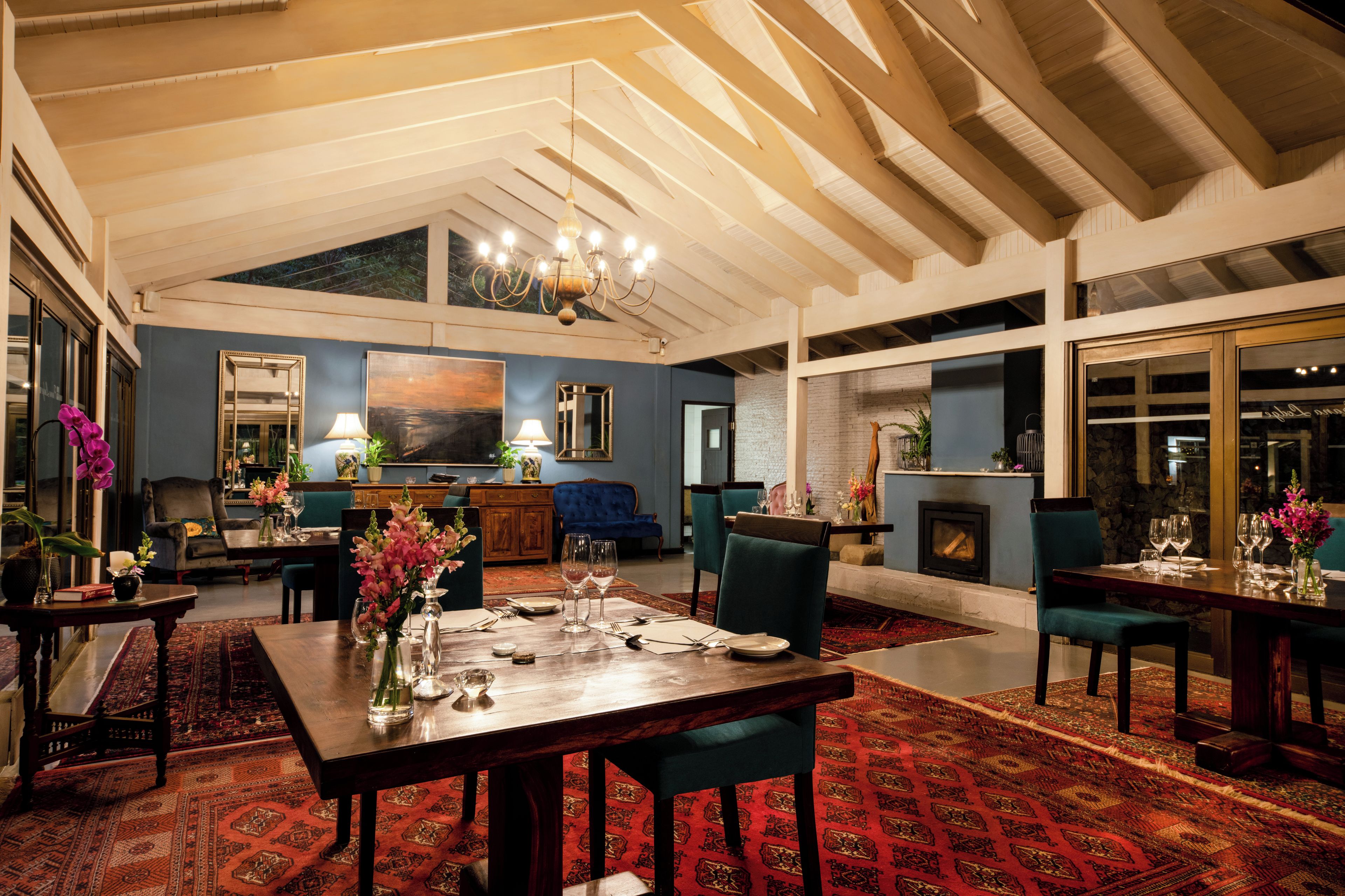 A spacious room with a high ceiling, a fireplace, and a dining area set for a meal.