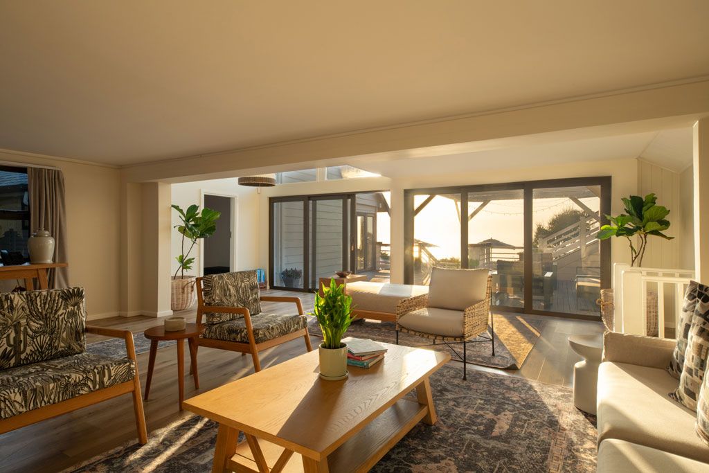 A spacious living area with a wooden coffee table, patterned sofas, and a large window offering a view of the cityscape.