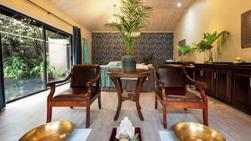 A room with a large window, a dining table with chairs, a potted plant, and a decorative bowl on the floor.