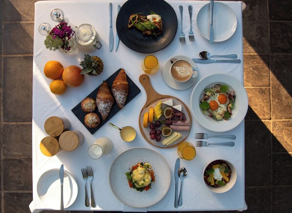 Un desayuno con diversos alimentos, utensilios y un mantel.