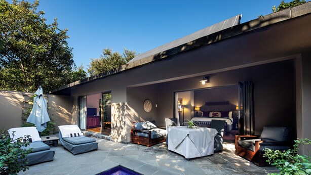 Un área de piscina exterior moderna con sillones, una mesa y un espacio de estar.