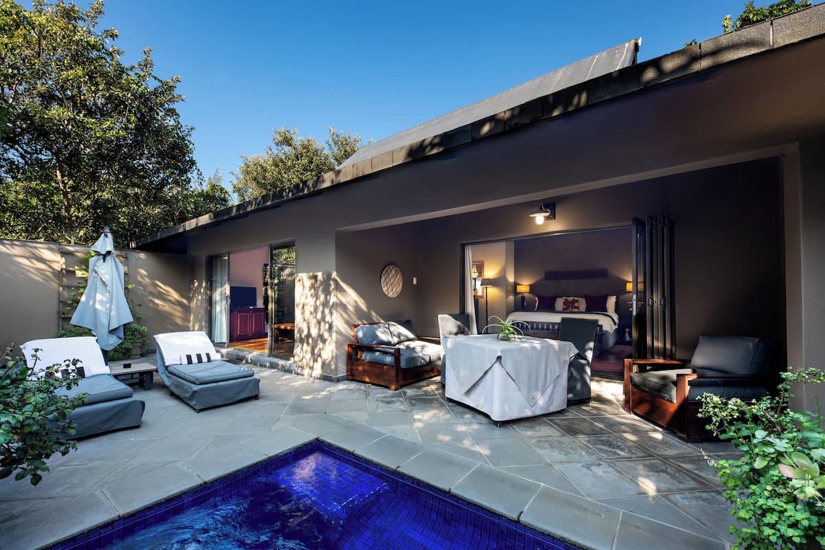 A modern outdoor pool area with lounge chairs, a table, and a seating area.