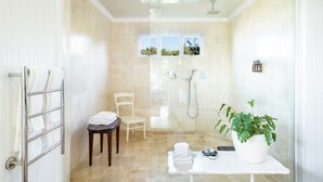 Un baño moderno con cabina de ducha de vidrio, un lavabo blanco y una planta en maceta.