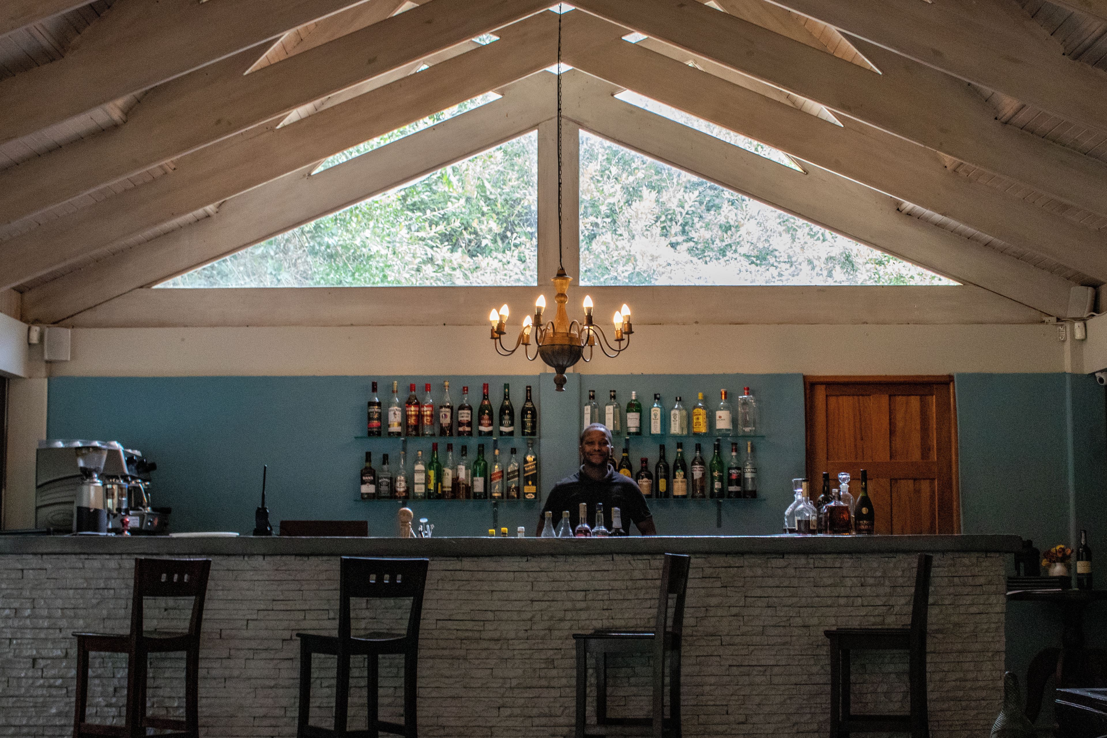 A bar area with a wooden ceiling, a chandelier, and a wall of liquor bottles.
