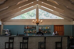 A bar area with a wooden ceiling, a chandelier, and a wall of liquor bottles. - Prana Lodge (Great Kei)