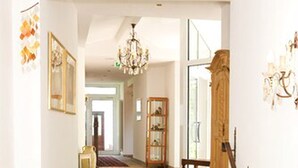 Una escalera conduce a una habitación con una araña, un armario de madera y una alfombra estampada.