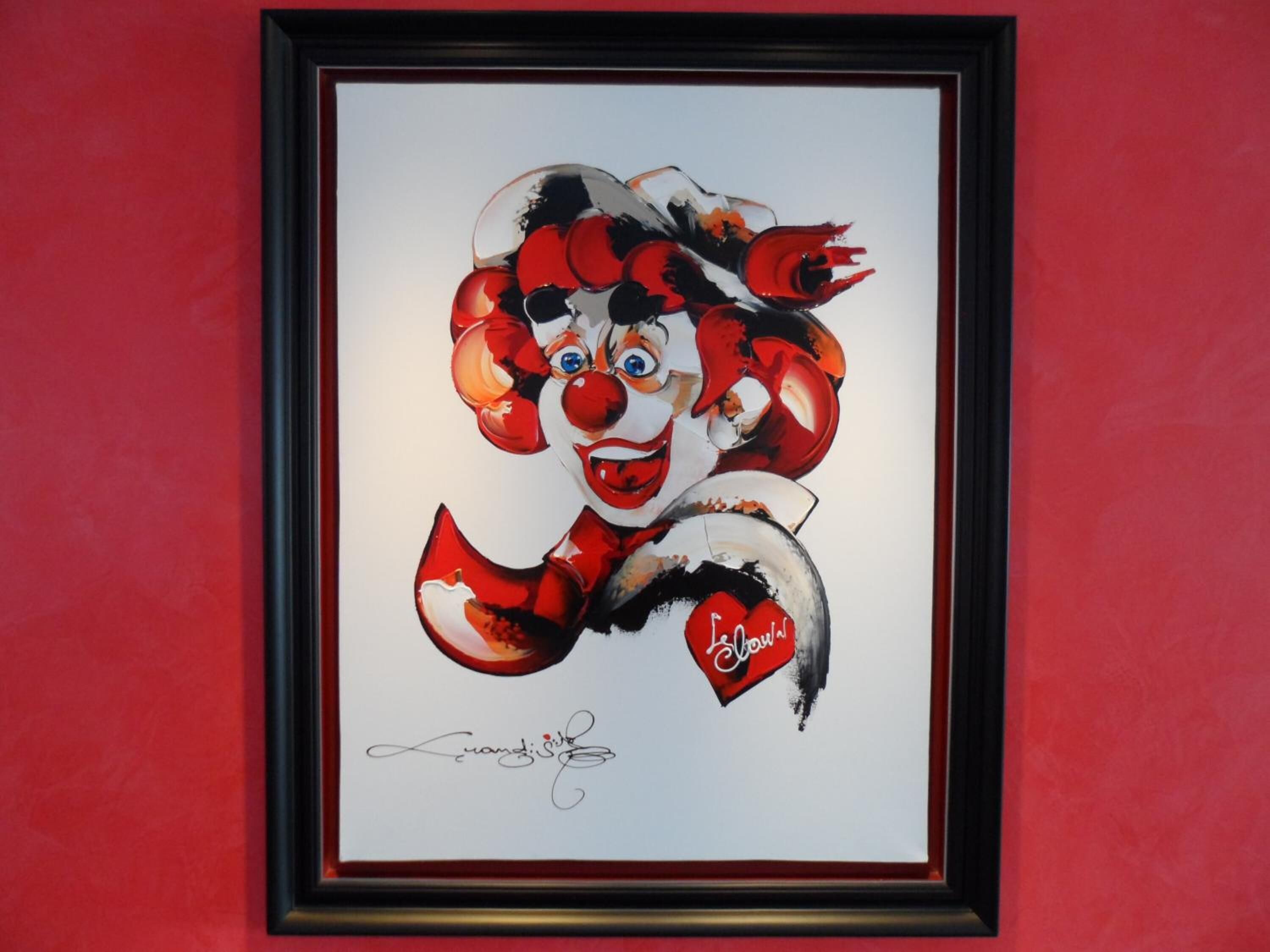 A framed artwork of a clown with a signature at the bottom.