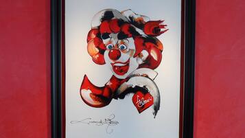 A framed artwork of a clown with a signature at the bottom.