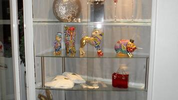 A display case with various decorative items including a golden trophy, a red candle, and a collection of colorful figurines.