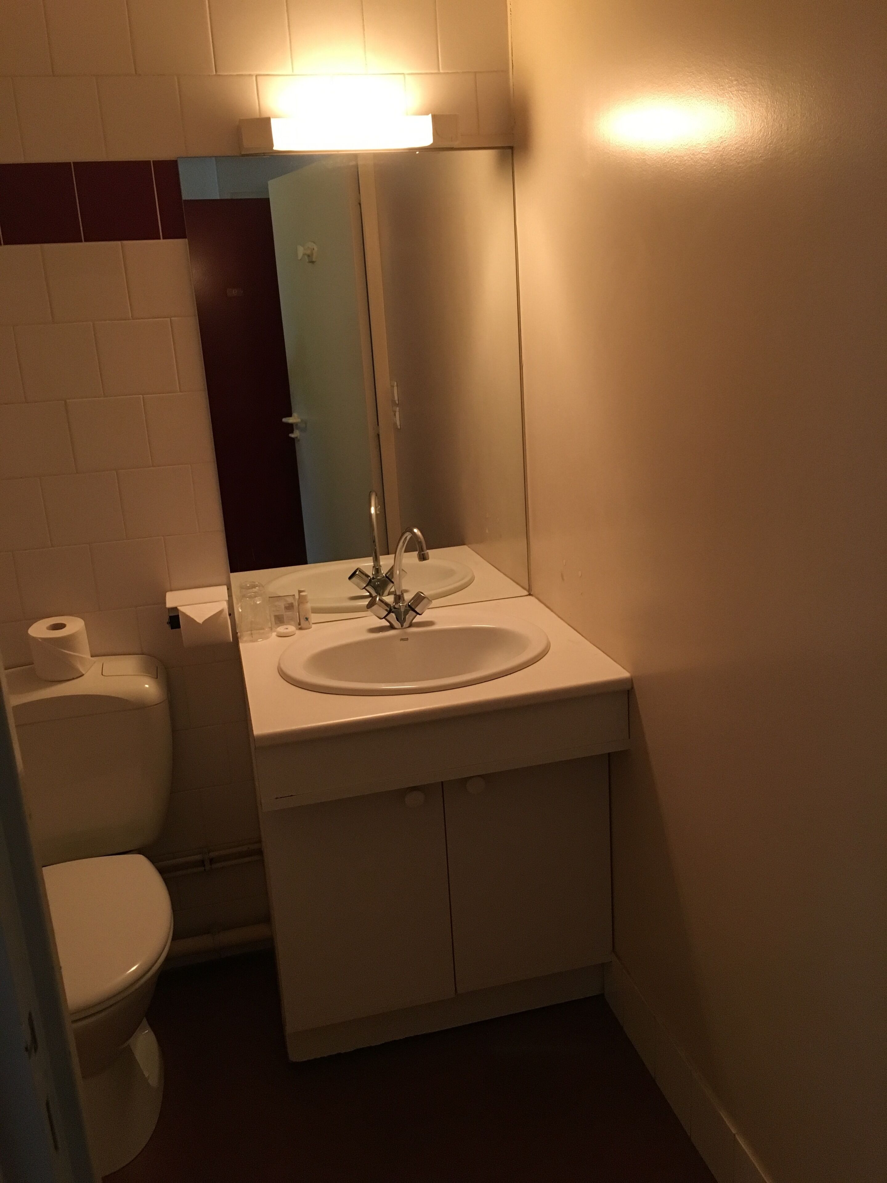 Een compacte badkamer met toilet, wastafel en spiegel.