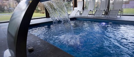 Una piscina cubierta, una piscina al aire libre, tumbonas