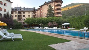 A hotel with a swimming pool, lounge chairs, and a mountainous backdrop. - Hotel Pessets & Spa (Sort)