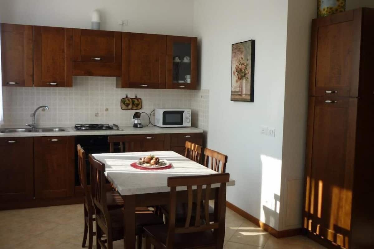 A kitchen with wooden cabinets, a microwave, and a dining table with chairs.