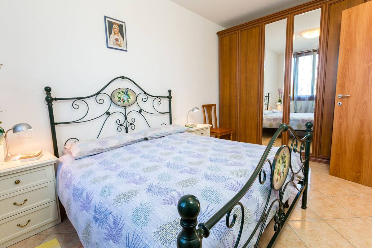 A bedroom with a bed, nightstands, a wooden wardrobe, and a mirror.