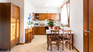 Una cocina compacta con armarios de madera, una encimera blanca y una mesa de comedor con sillas.