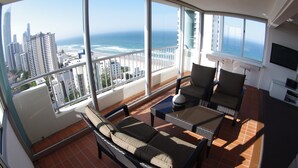 A balcony with a view of the ocean and cityscape, furnished with wicker chairs and a sofa. - Marriner Views (Surfers Paradise)