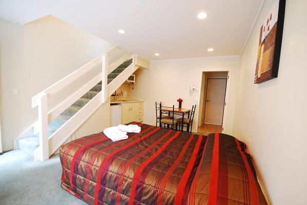 Un dormitorio con cama, una escalera, un escritorio y una silla.
