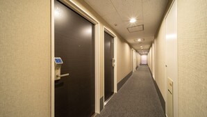 A hotel hallway with doors numbered 703 and 704, carpeted floors, and a ceiling with recessed lighting.