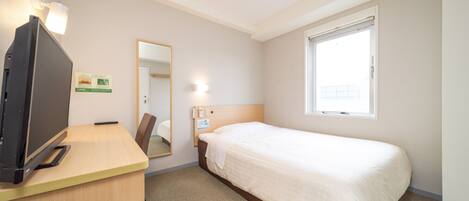 A hotel room with a bed, a desk with a television, a mirror, and a window.