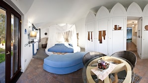 A room with a bed, a blue sofa, a glass table, and a wardrobe with doors. - Villa Angelina (Massa Lubrense)