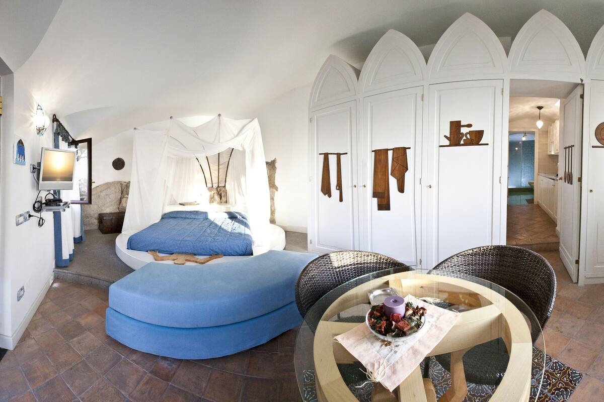 Ein Zimmer mit einem Bett, einem blauen Sofa, einem Glastisch und einem Schrank mit Türen.