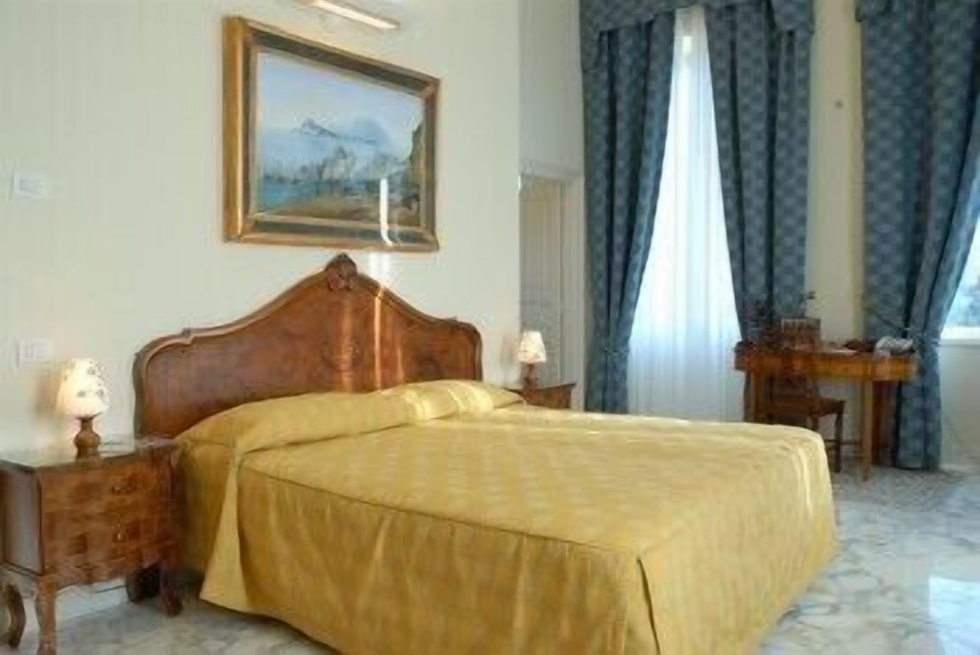 Una habitación de hotel con una cama grande, cabecera de madera, un escritorio y un cuadro en la pared.
