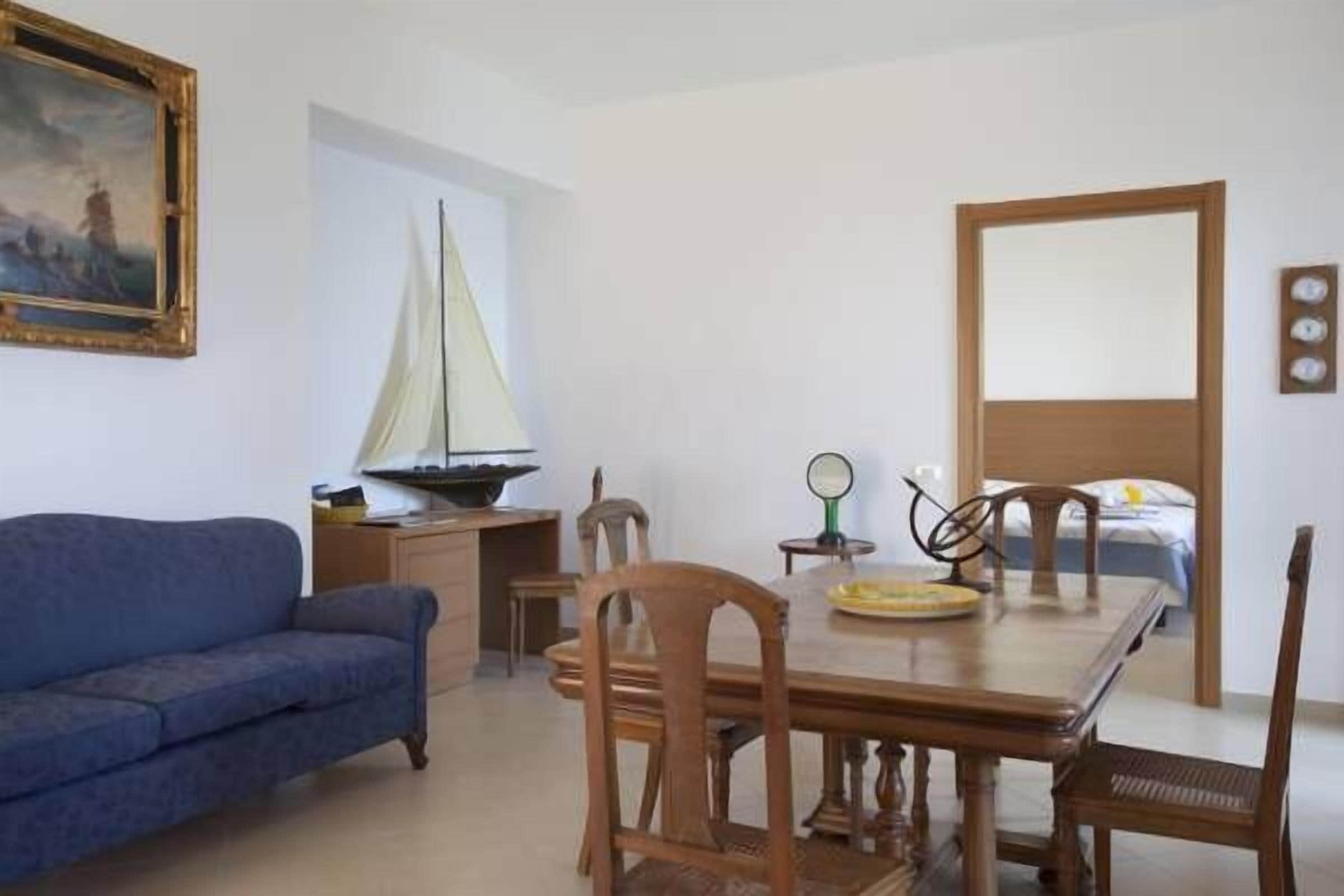 Una stanza con un tavolo da pranzo in legno, un divano blu e un modellino di una barca a vela.