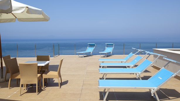 A rooftop terrace with lounge chairs and a table, overlooking the sea. - Villa Angelina (Massa Lubrense)