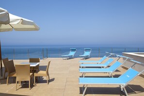 A rooftop terrace with lounge chairs and a table, overlooking the sea. - Villa Angelina (Massa Lubrense)