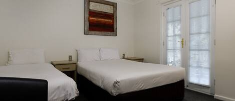A hotel room with two beds, a painting on the wall, and a door with blinds.