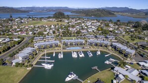 An aerial view of a marina with boats docked, surrounded by residential buildings and greenery.