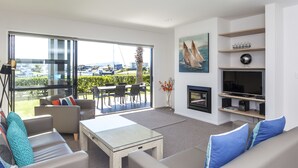A modern living room with a glass coffee table, sofas, a TV, and a fireplace.