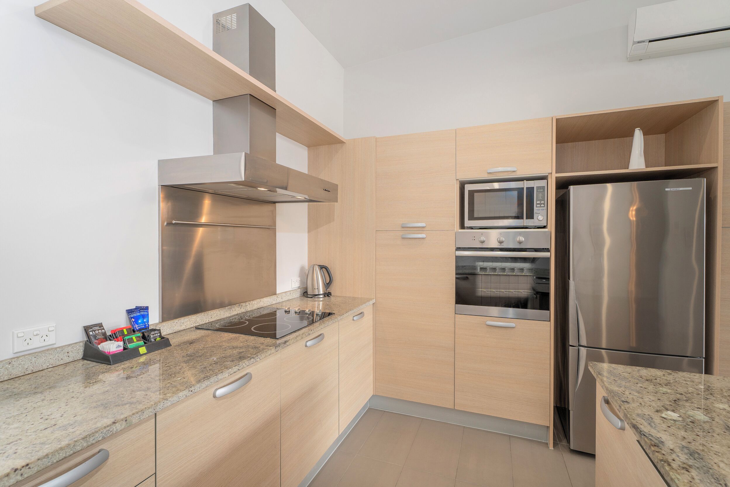 A modern kitchen with stainless steel appliances, wooden cabinets, and a granite countertop.