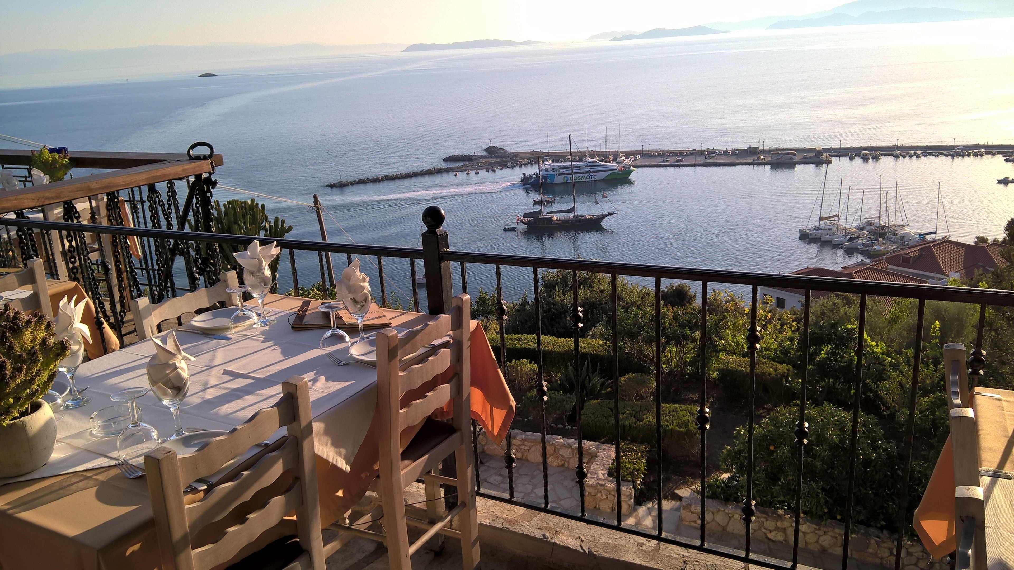 Mesa lista para comer con vista al mar y barcos.