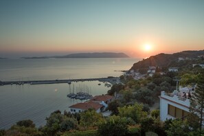 A coastal view with a marina, boats, and buildings with red-tiled roofs. - Aegean Wave Hotel (Skopelos)