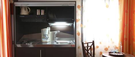 A compact kitchen with a built-in oven, a coffee maker, and a sink.