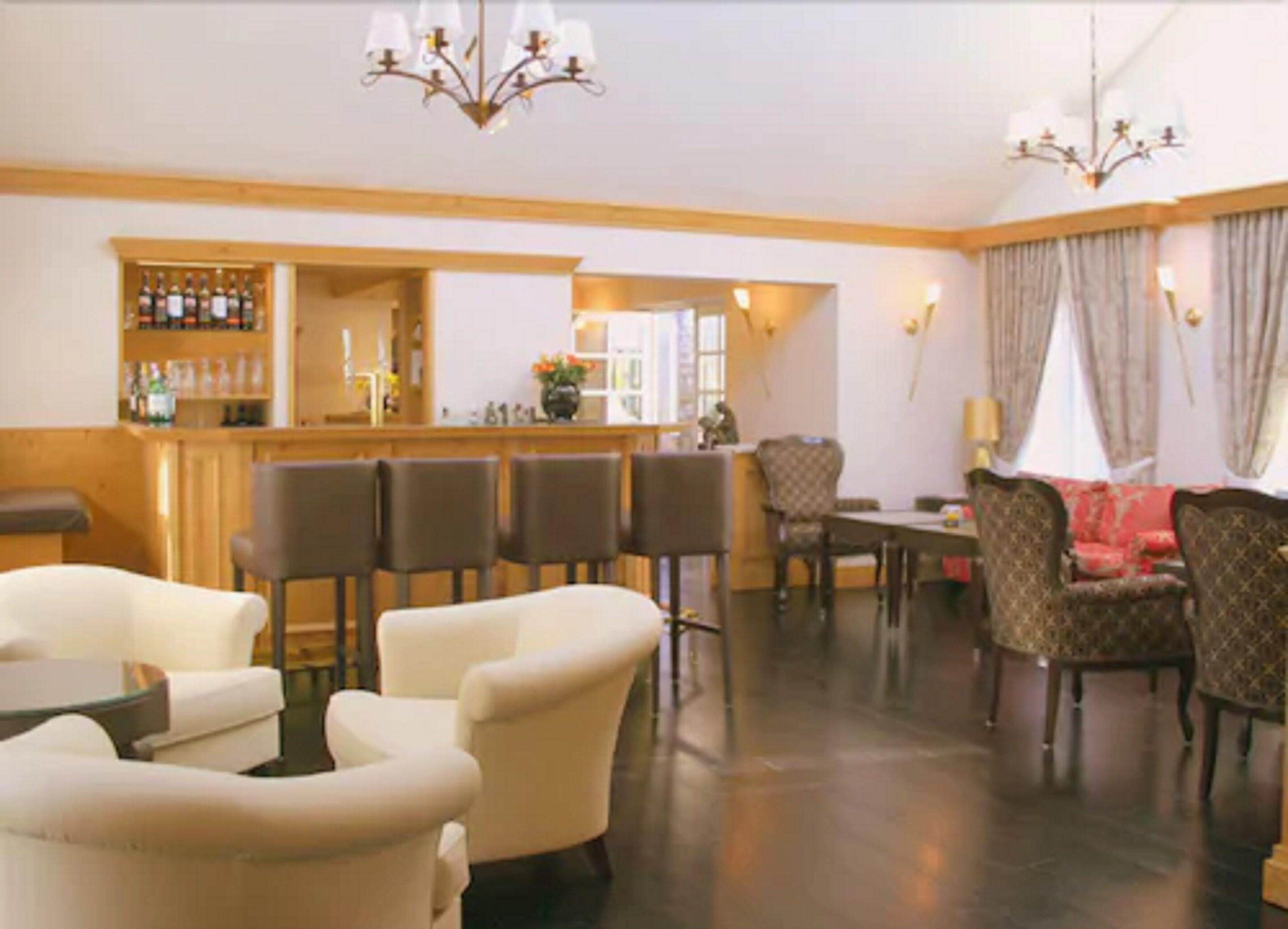 Un hall d’hôtel comprenant un bar, des espaces aménagés avec des sièges et un lustre.