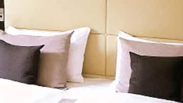 A bed with white bedding and two pillows, one dark and one light.