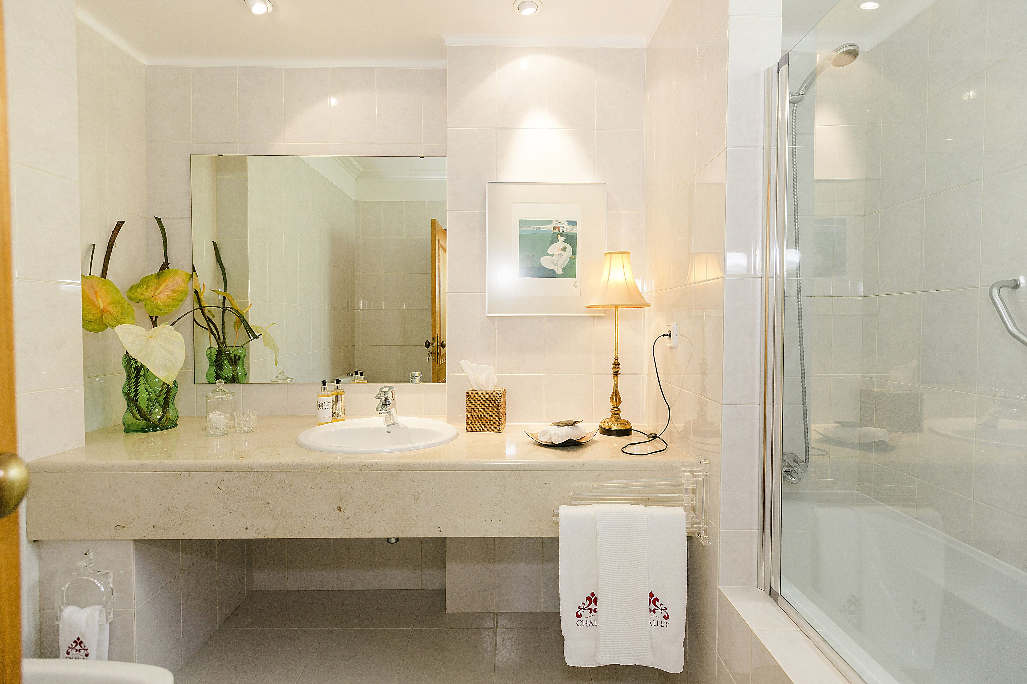A bathroom with a sink, mirror, and shower.