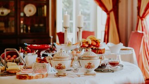 Una mesa de comedor dispuesta con diversos platos, incluyendo pan, pastelería y un frutero.