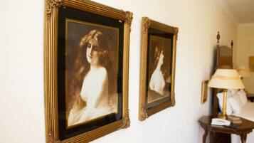 Dos retratos enmarcados en una pared, una lámpara y una mesita de noche con un teléfono.