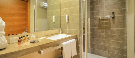 A modern bathroom with a large mirror, a sink, a shower, and a towel rack.