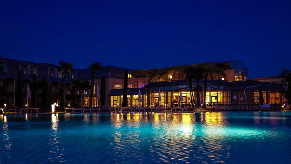 Een binnenzwembad, een buitenzwembad en parasols bij het zwembad